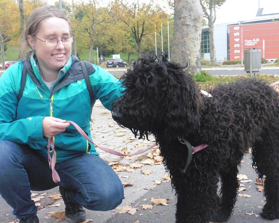 Kniende Frau streichelt Hund.
