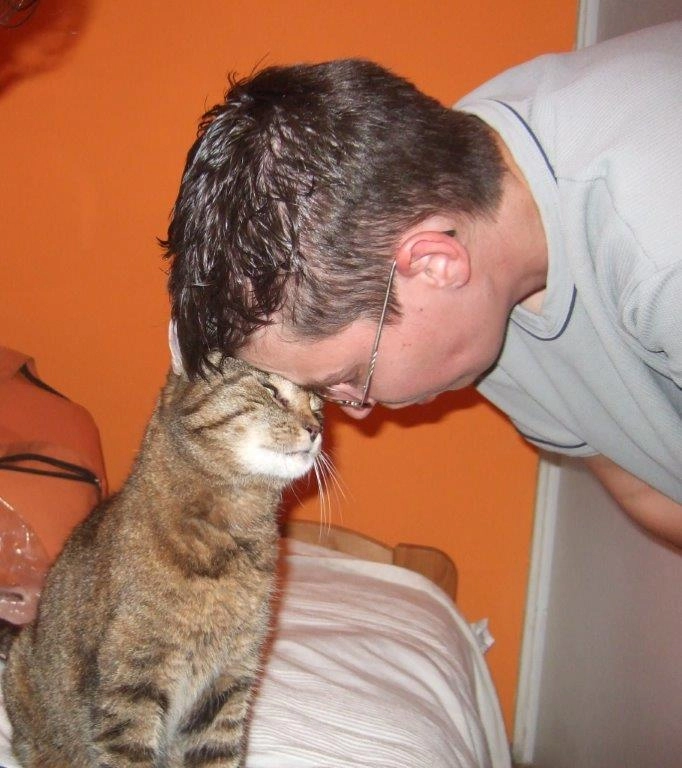Frau mit Brille stößt ihre Stirn sanft an die Stirn einer Katze.