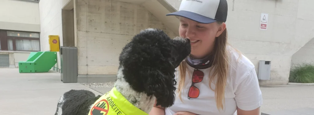 Frau kniet am Boden und lächelt Hund an.