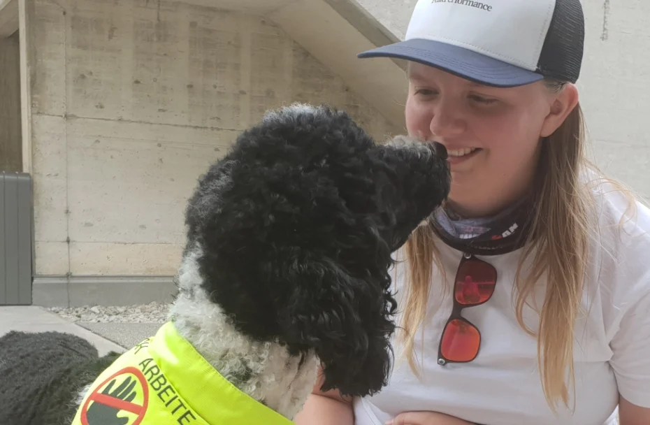 Frau kniet am Boden und lächelt Hund an.