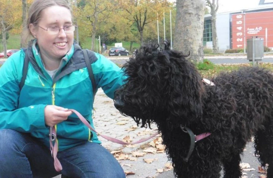 Lächelnde Frau kniet am Boden und streichelt Hund.