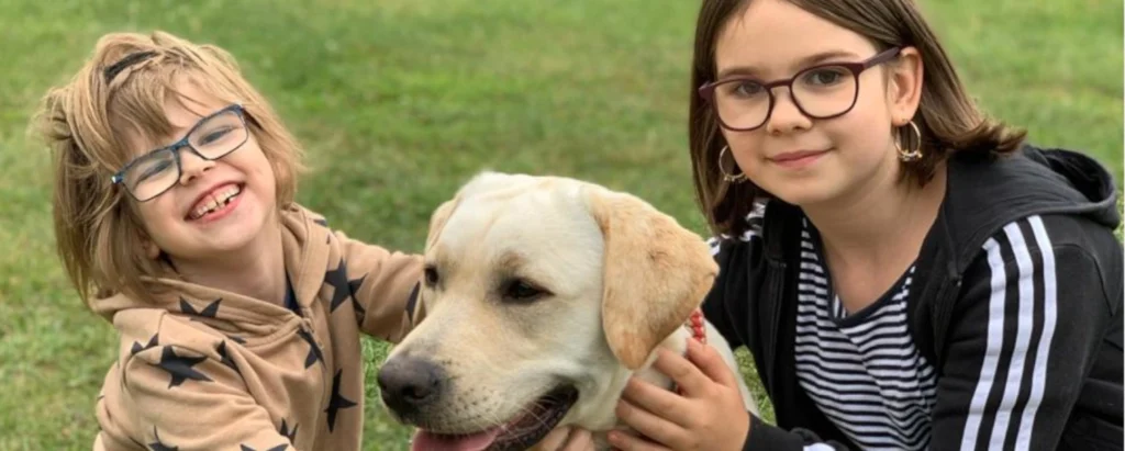 Zwei Kinder lächeln und streicheln einen Hund.