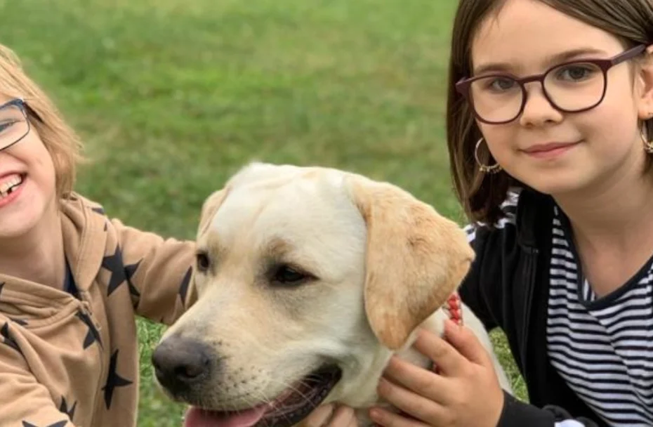 Zwei Kinder lächeln und streicheln einen Hund.