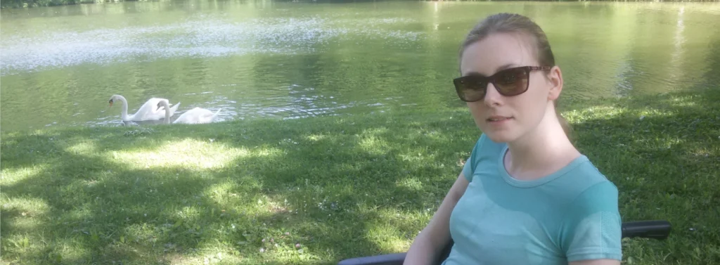 Frau sitzt in Wiese vor See.