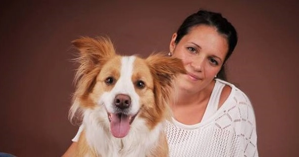 Lächelnde Frau und Hund vor dunklem Hintergrund.