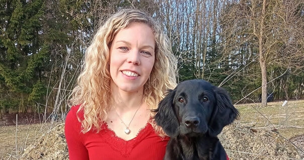 Lächelnde Frau und Hund im Wald.
